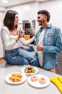 Young couple sharing a moment together over coffee, pastries, and strawberries in their