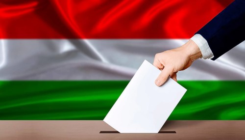 Hand placing a ballot in ballot box with the Hungarian flag in the background. Hungary