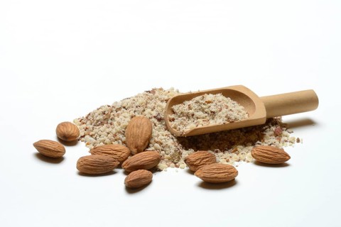 Almonds and ground almonds with wooden scoop, Prunus amygdalus