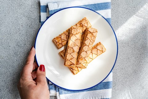 Delicious puff pastry sticks glazed with sweet apricot jam are beautifully arranged on a white