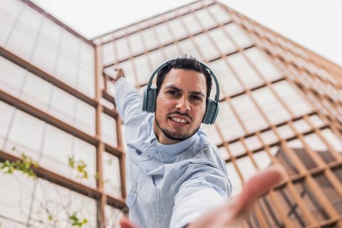 A young Cuban man in a light blue shirt, wearing headphones, strikes a dynamic dance pose. He