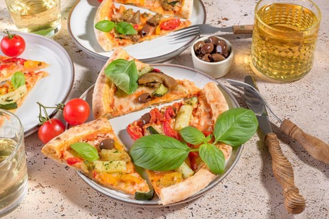 Enjoy a mouthwatering vegetarian pizza topped with fresh basil, zucchini, eggplant, peppers, and