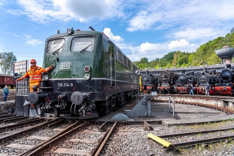 Freight train electric locomotive E 40 1314 at the ring locomotive shed with many historic steam