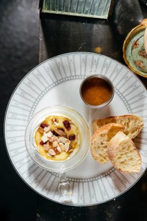 A delectable serving of creamy camembert adorned with honey sauce, crunchy nuts, and tangy