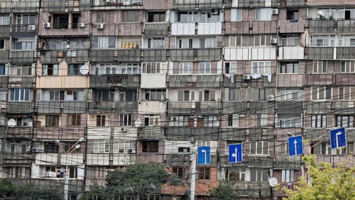 Façade of an old apartment block full of cables and road signs in the foreground, Yerevan, Armenia
