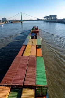 Container cargo ship on the Rhine, heading south, the crane houses in Cologne at the
