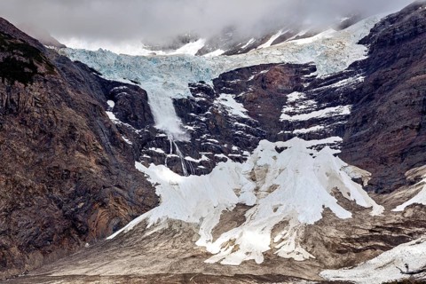 Majestic glacier landscape with rugged rocks and snow under a dramatic cloud cover, The glaciers of