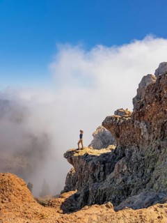 Distant side view of woman standing on the rugged terrain of Pico de las Nieves, Gran Canaria,
