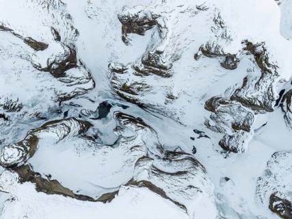 This aerial photo captures the abstract patterns of Iceland's snow-covered terrain, where rugged