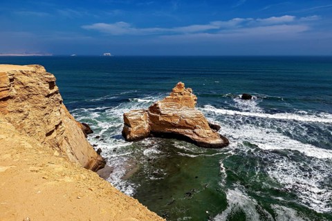 Coastal landscape with rocky cliff and calm blue sea under a clear sky, The rocky coast near