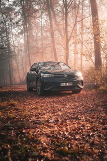 A Volkswagen parked in a quiet forest full of autumn leaves in the early morning fog, electric car