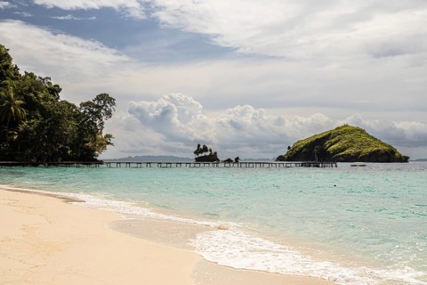 From above, this aerial image captures the serene beach and crystal clear waters of the Raja Ampat