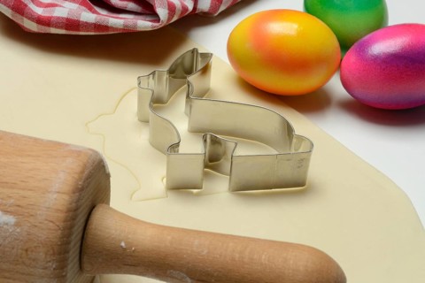 Rolled dough with bunny cookie cutter, rolling pin and Easter eggs
