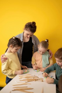 Children engage in a creative art class, guided by a teacher. They use vibrant modeling clay and