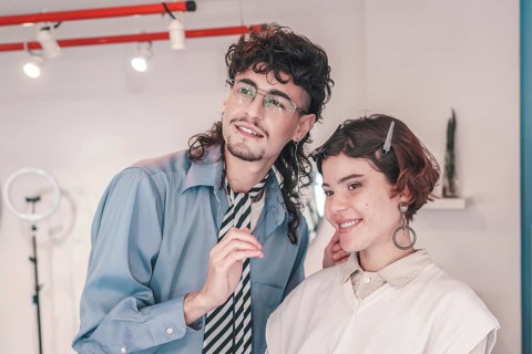 In a brightly lit salon, a friendly hairdresser styles a client's hair, showcasing a welcoming