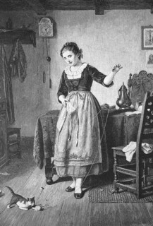 Woman playing with a ball of wool with a cat, Living room, Germany, Woman in traditional dress