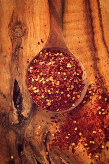 Red pepper flakes, in a wooden spoon, on a wooden table, rustic style, no people