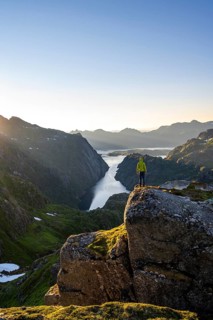 Mountaineer, young man in front of mountain landscape at sunrise, fjord Trollfjord and Raftsund,
