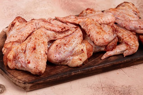 Chicken wings, marinated and laid out on a wooden platter, ready for cooking, grilling or baking,