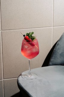 A refreshing berry gin tonic garnished with raspberries, currants, and mint. Served in a