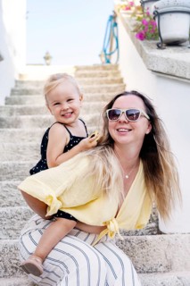 A joyful mother and her daughter share a playful moment outdoors on a bright day. They embody