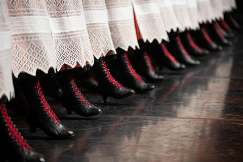 Detail of dancer's legs with black shoe and red laces