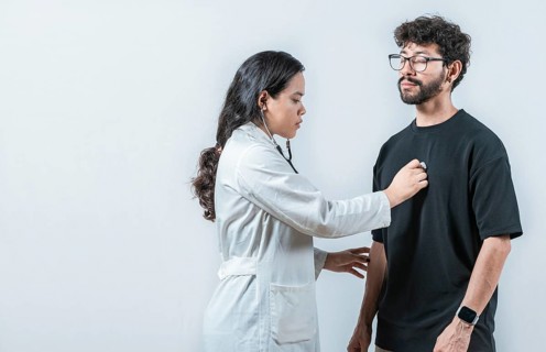 Young Asian doctor checking a male patient heart with a stethoscope, isolated. Asian doctor