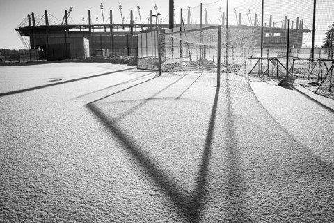 Frozen football pitch covered by snow and stadium in the background