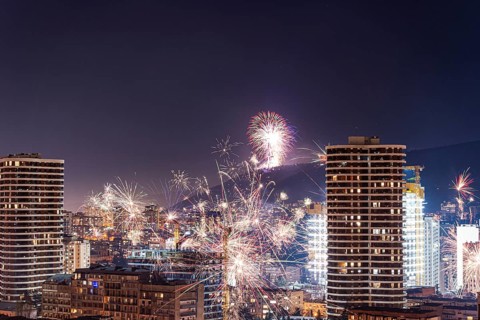 Vibrant fireworks light up the night sky over Tbilisi's downtown, illuminating the cityscape with