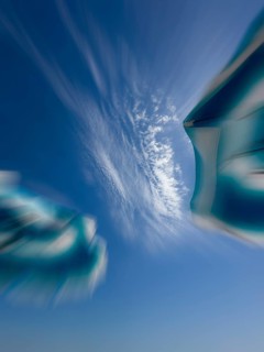 Parasols in front of a blue sky with clouds, zoom effect