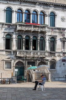 Gondolier sitting on a chair, waiting for customers, Venice, Italy