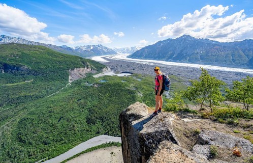 Young woman on a rocky outcrop enjoying the view, view of impressive mountain landscape with