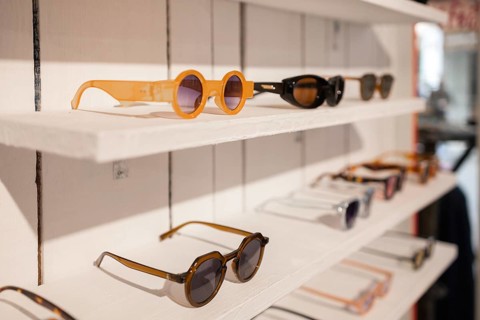 A variety of stylish sunglasses displayed on neatly arranged white shelves in a trendy store