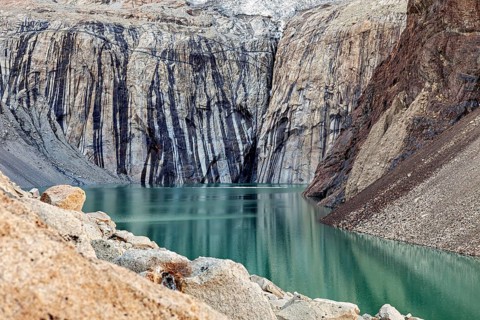 Turquoise-coloured lake with steep, layered rock faces that create a peaceful and natural