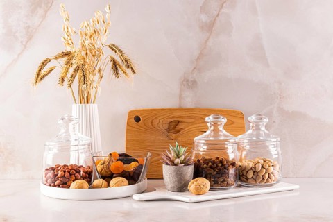 Elegant kitchen countertop display with dried wheat, wooden cutting board, and glass jars filled