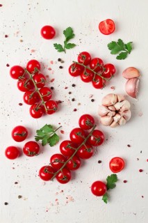 Branch with mini cherry tomatoes, with spices and herbs, garlic, food background, top view, on a