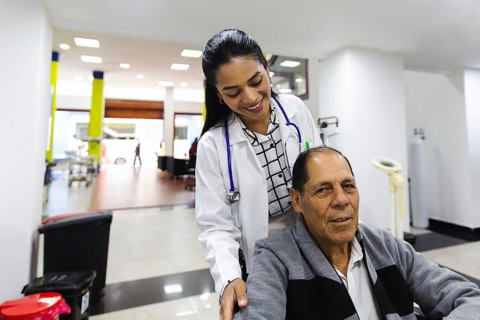 A compassionate doctor in a hospital assists an elderly man in a wheelchair, showcasing the