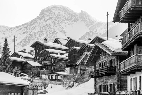 Snow-covered old farmhouses, large wooden cross, black and white photo, historic town center,