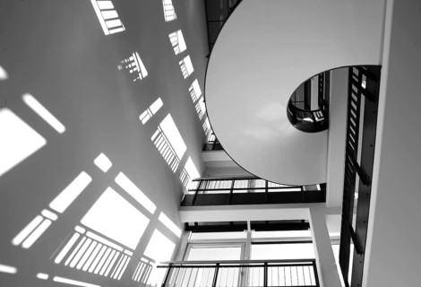 A black stair railing casts shadows on a white wall in the stairwell, Berlin