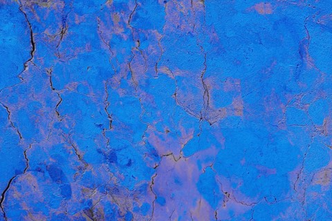 Close-up of a cracked blue textured concrete surface, showcasing intricate patterns and rough