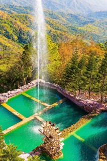 Turquoise green pond with fountain and water feature in the Wat Phra That Sorn Kaew Buddhist temple