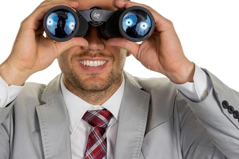 A manager (young entrepreneur) with binoculars looking for orders or jobs, studio shot