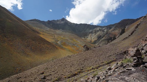 Slope with rocky surface under blue sky with white clouds, trekking at Stok La Pass in Ladakh,