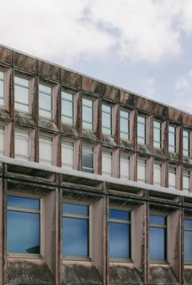 Close-up shot of a weathered brutalist architecture building facade, featuring rows of windows