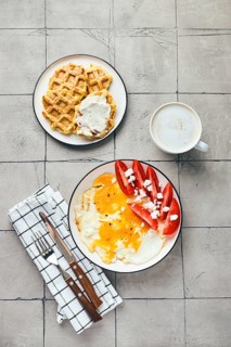 Top view of homemade breakfast or brunch. Fried egg with feta cheese and tomato, and belgian