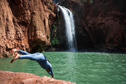 OUZOUD, MOROCCO - OCTOBER 5, 2024: A Moroccan woman in swimsuit jumps headfirst into the water