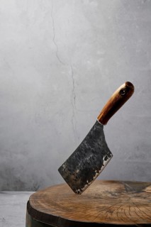 Old butcher's cleaver sticking out of a wooden chopping log