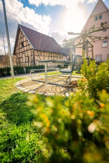 Sunlit bench in a park surrounded by half-timbered houses and green lawns, Deufringen, Aidlingen,