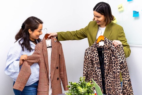 Two women engage in an image consulting session, discussing fashion choices. One holds a plaid