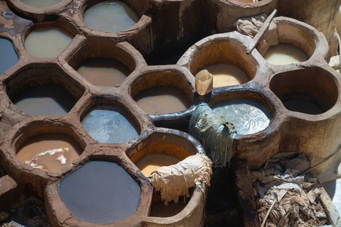Aerial view of traditional leather tanning pits filled with vibrant dye baths in warm sunlight in
